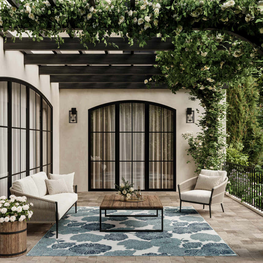 Outdoor patio with white seating and Nourison Garden Oasis Blue Tropical Area Rug with floral pattern.
