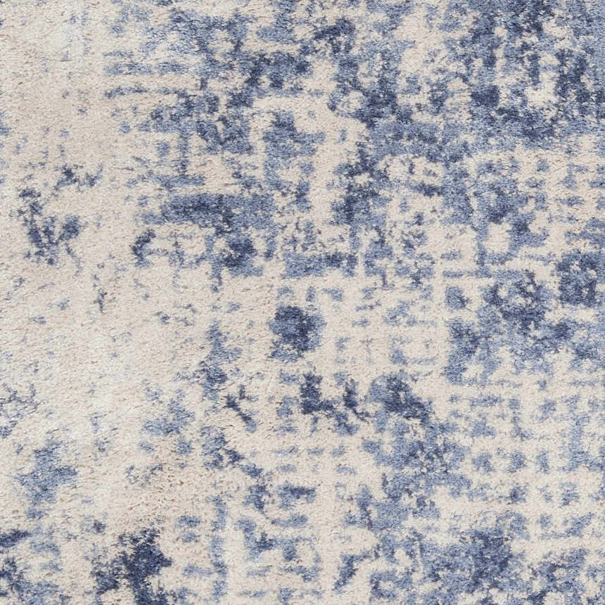 Close-up of Nourison Silky Textures Ivory/Blue rug. Abstract pattern with soft blue and ivory tones, plush texture.