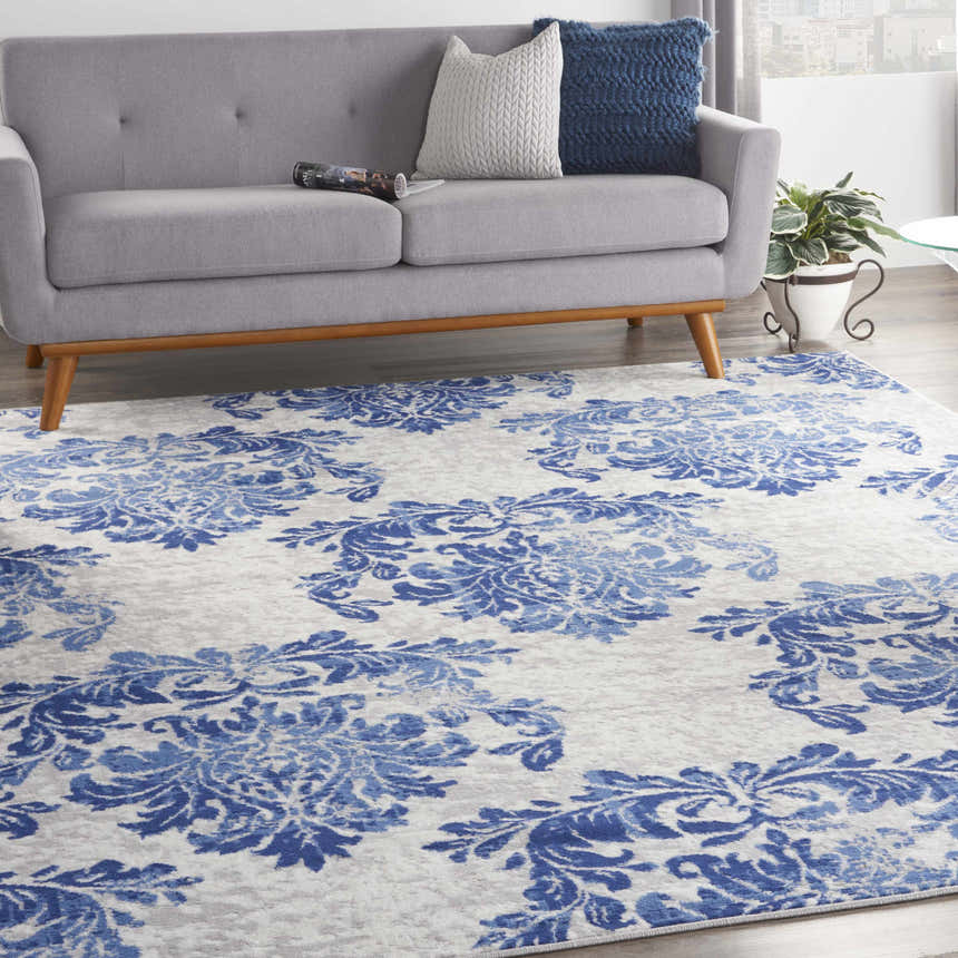 Living room with gray sofa and Nourison Whimsicle Ivory Navy rug featuring a blue floral pattern.