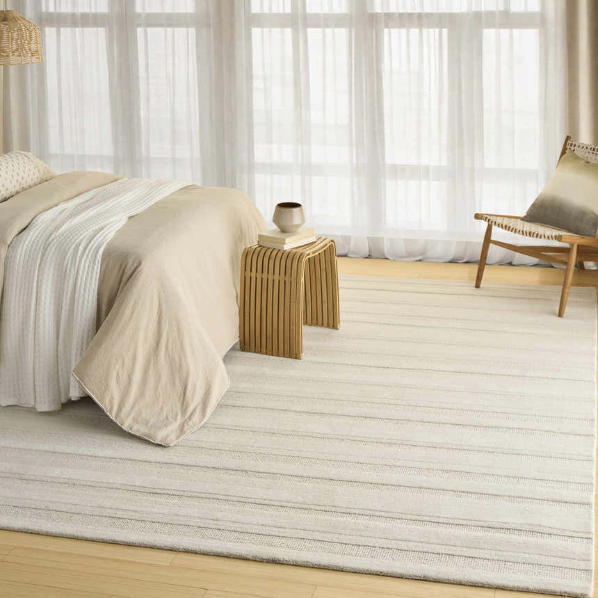 Serene bedroom scene with a DKNY Pure Multi Weave Ivory rug, wood accents, and soft neutral tones.