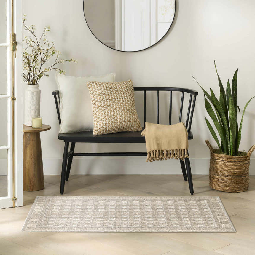 Entryway with a Nourison Nordic Beige Modern rug, black bench, round mirror, and potted snake plant.
