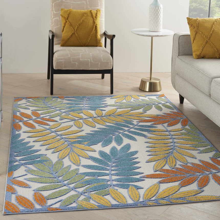Living room scene with a Nourison Aloha Ivory Multicolor Tropical Area Rug, sofa, and chair.