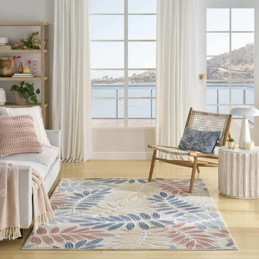 Coastal living room with Nourison Aloha Ivory Blue rug, white sofa, and ocean view.