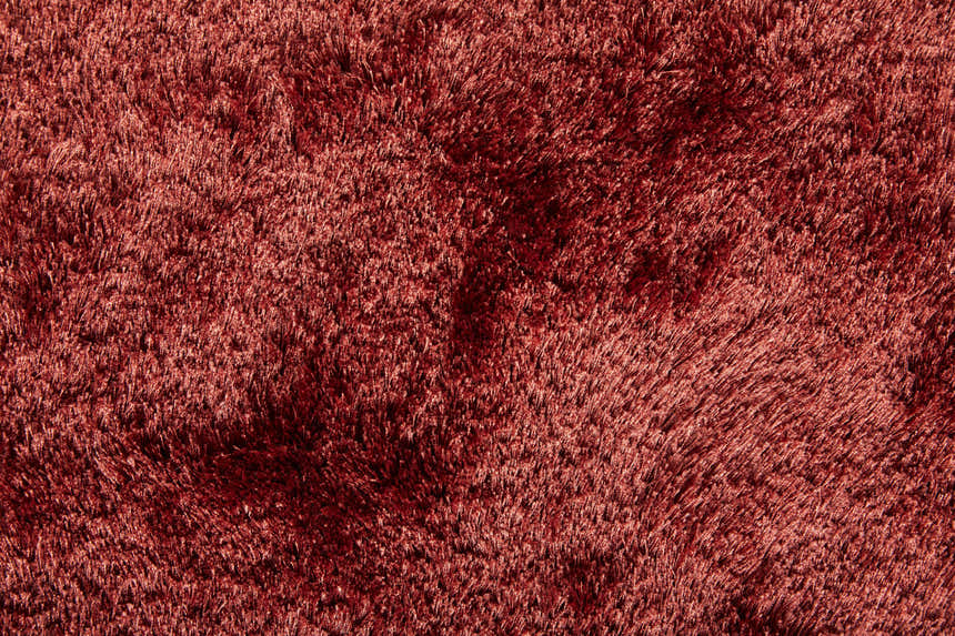 Close-up of the plush texture and rich red-orange color of the Feizy Indochine Modern Solid Area Rug. Texture