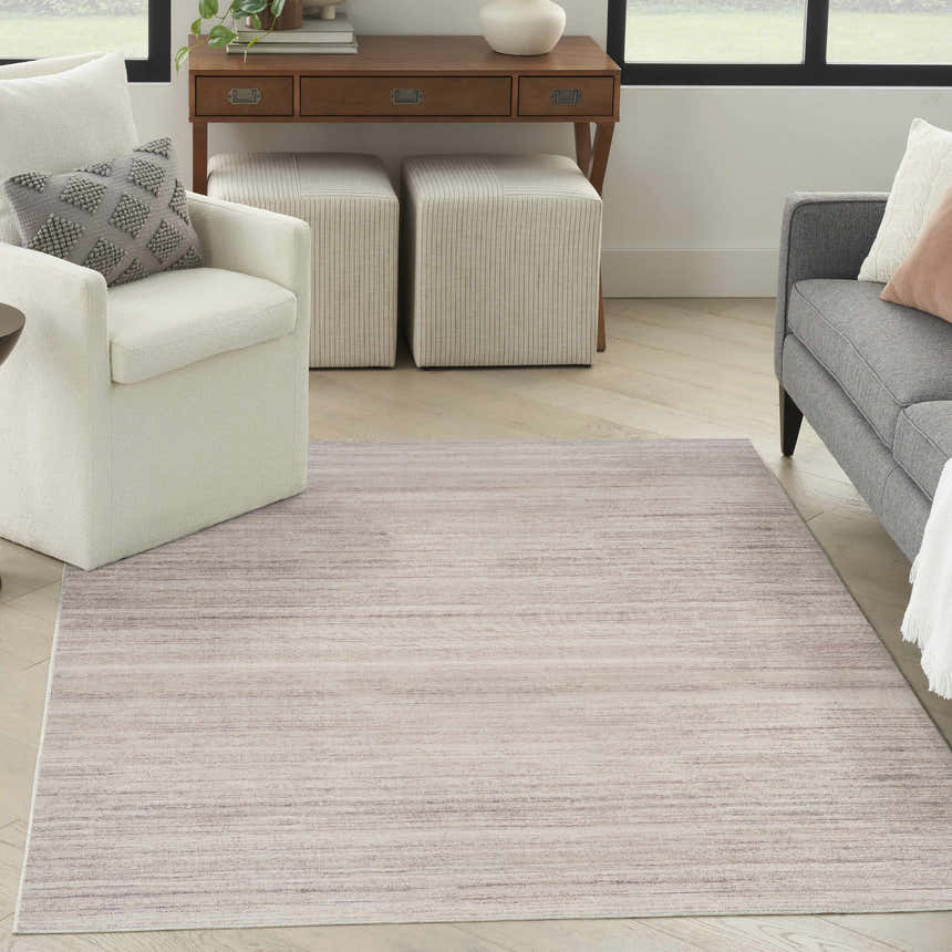 Living room scene with a Nourison Essentials Ivory Mocha rug, white armchair, gray sofa, and wood desk.