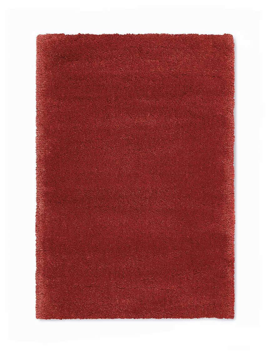 Close-up of a plush, burgundy Calvin Klein Brooklyn area rug. The rug has a shag texture and a rectangular shape.