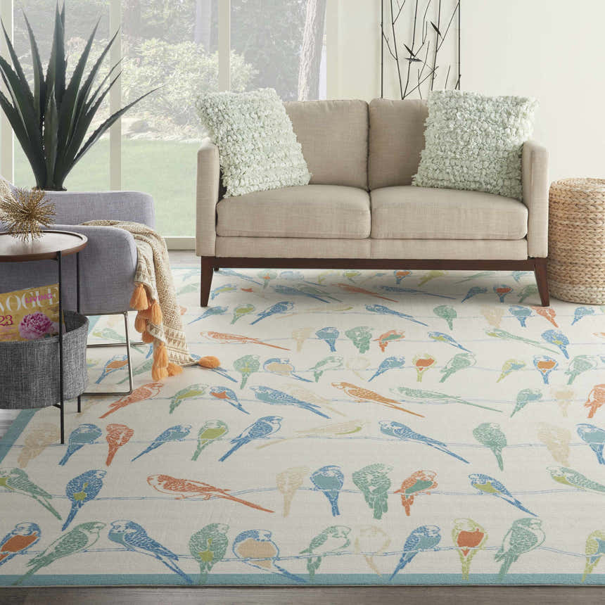 Living room scene with Waverly Sun N' Shade Multicolor Tropical Area Rug, beige sofa, and natural light.