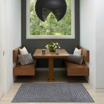 Dining nook with a Nourison Tulum Denim Outdoor Area Rug, wood table, and built-in benches.