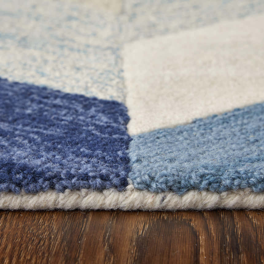 Close-up of the Feizy Arazad rug showing its blue, ivory, and gray geometric pattern and hand-tufted wool texture. Pile