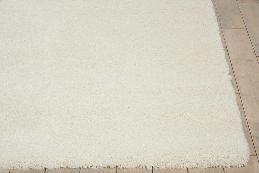 Close-up of the plush texture of the Nourison Malibu Shag Ivory rug on a light wood floor.