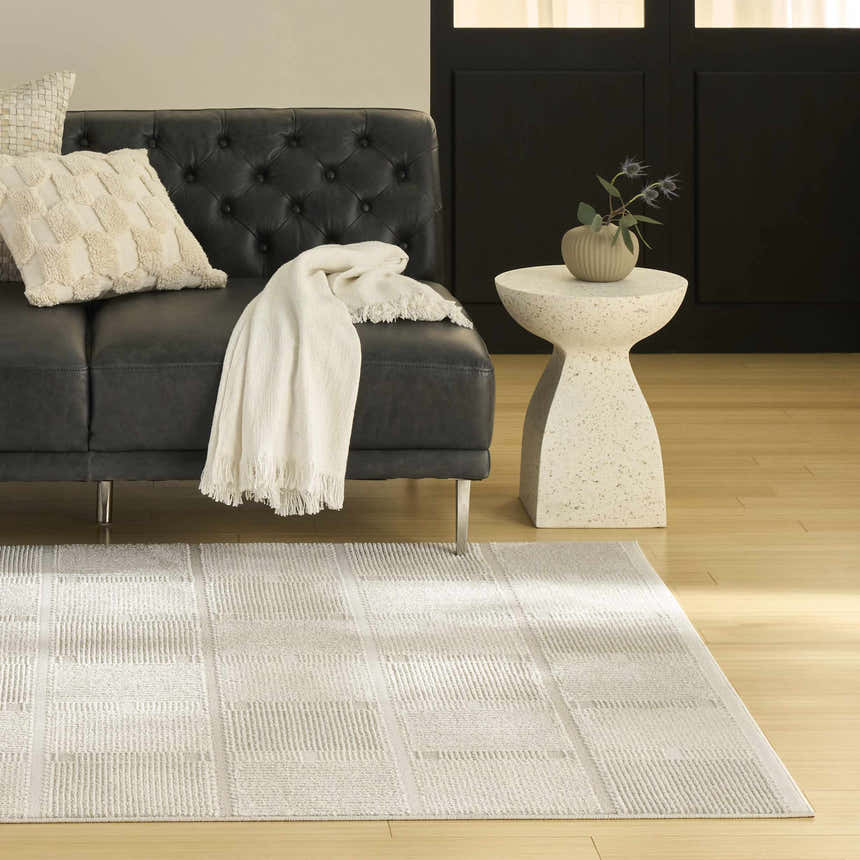 Modern living room with a black leather sofa and Nourison Nordic Ivory Beige area rug.