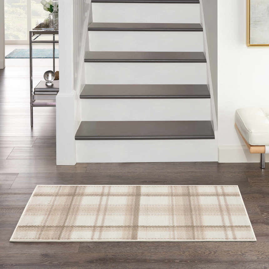 Entryway scene with a Nourison Grafix Ivory Beige rug, farmhouse style, with a plaid pattern on dark wood floors.