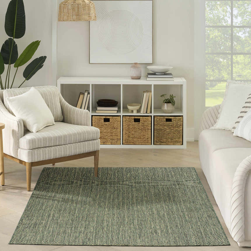 Living room with a green Nourison Horizon Indoor/Outdoor Area Rug, neutral furniture, and natural light.