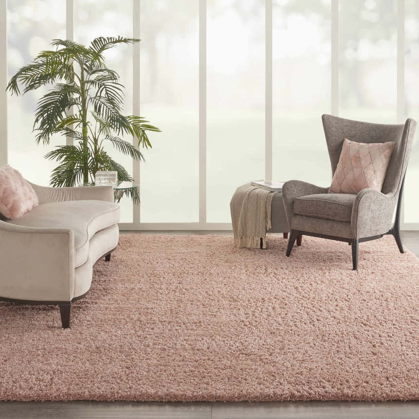 Living room scene with blush pink Nourison Malibu Shag rug, chaise lounge, chair, and large window.