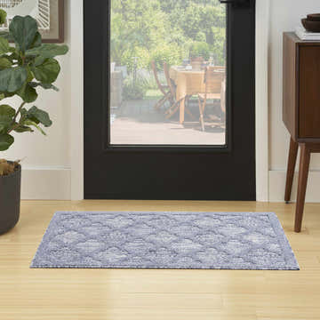 Entryway with Nourison Easy Care Denim Blue Modern Area Rug, wood floors, black door, and view of outdoor dining.