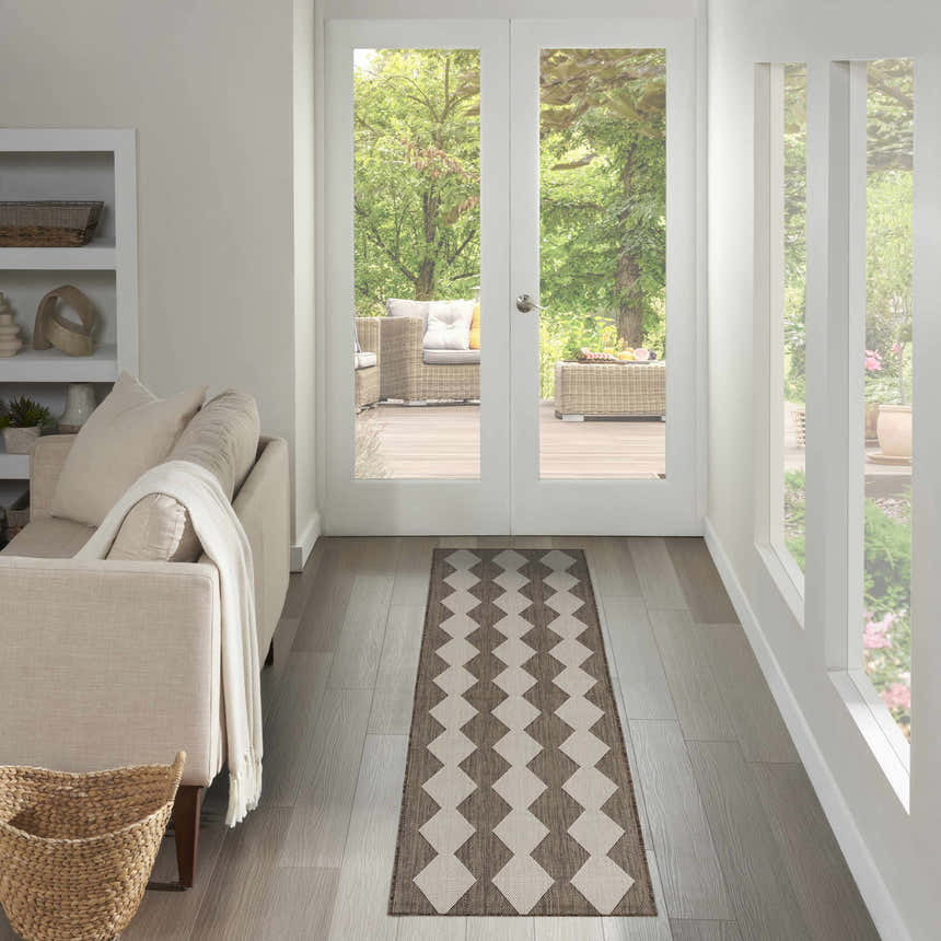 Hallway scene with a Nourison Positano Natural runner rug, light wood floors, and a view to an outdoor patio.