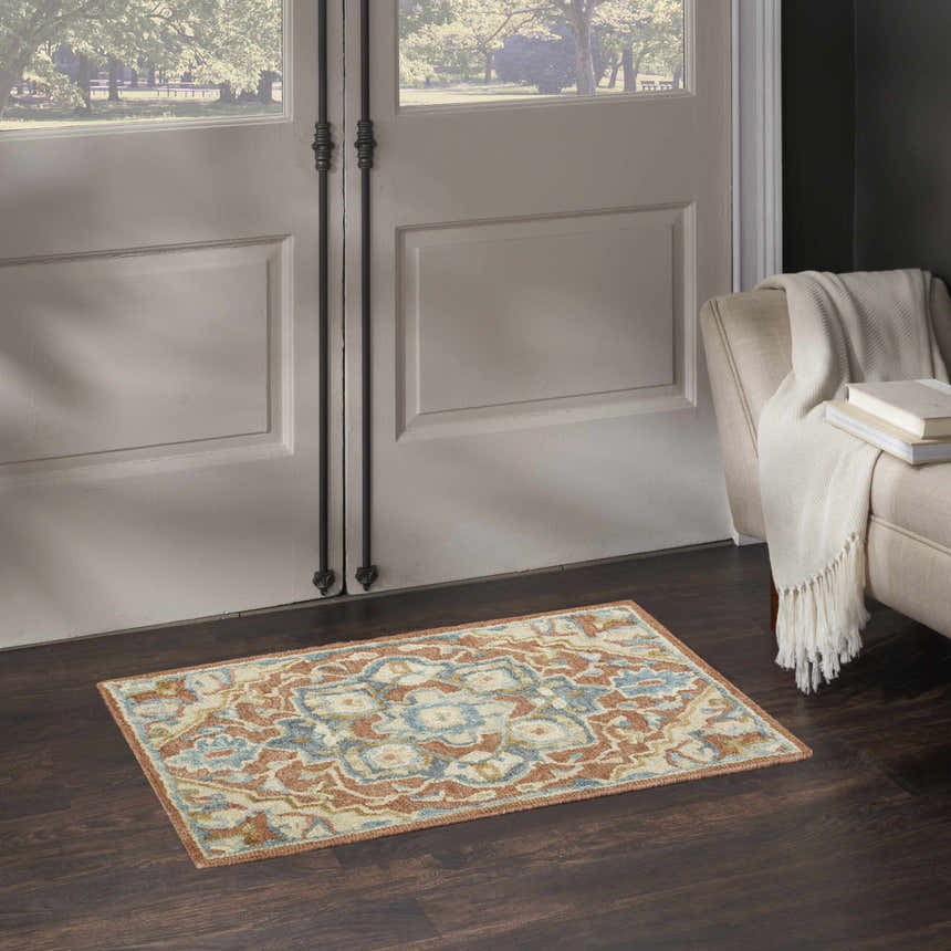 Entryway with Nourison Maison Rust Ivory Vintage rug, dark wood floors, and neutral armchair.