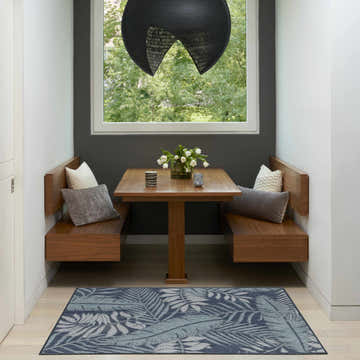 Breakfast nook with wood benches and table, featuring the Nourison Garden Oasis Navy Outdoor Area Rug.