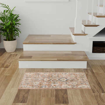 Entryway with wood floors and Nourison Oushak Home Rust Vintage Indoor Area Rug at the base of the stairs.