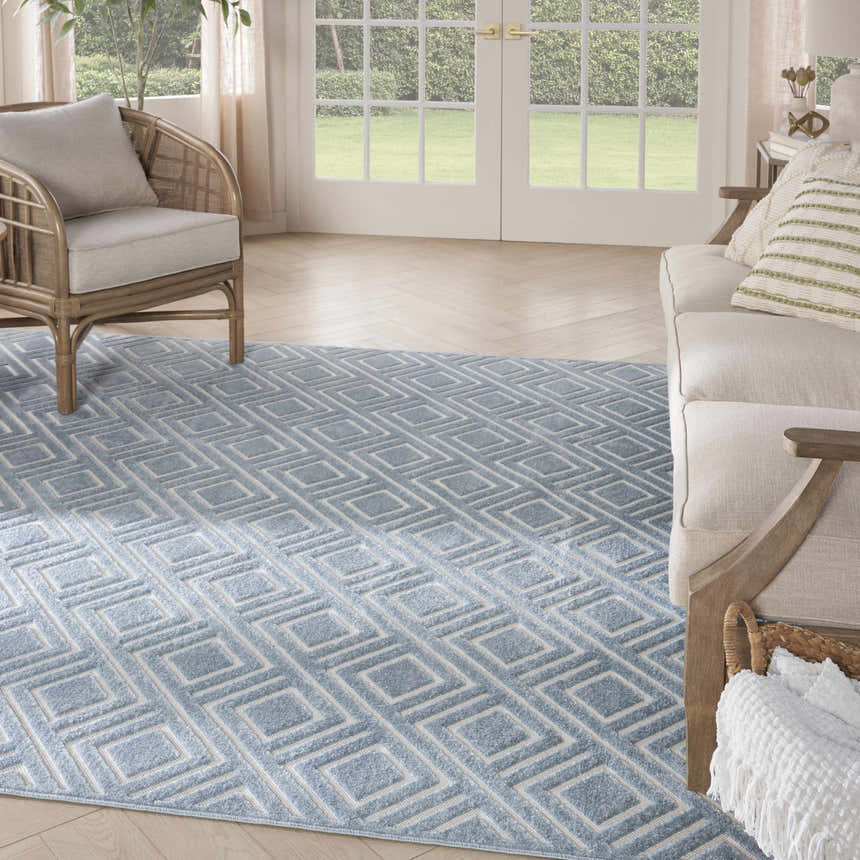 Living room scene with a light blue Nourison Care Free rug featuring a modern geometric diamond pattern.