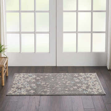 Entryway with grey wood floors and Nourison Tranquil Grey Beige rug with floral pattern near white french doors.
