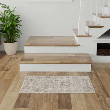 Entryway scene with Nourison Oushak Home Mint Vintage Indoor Area Rug, wood floors, white stairs, and potted plant.