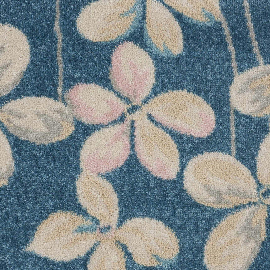 Close-up of Nourison Tranquil Turquoise rug, showing floral pattern in aqua, beige, and pink hues. Soft, textured weave.