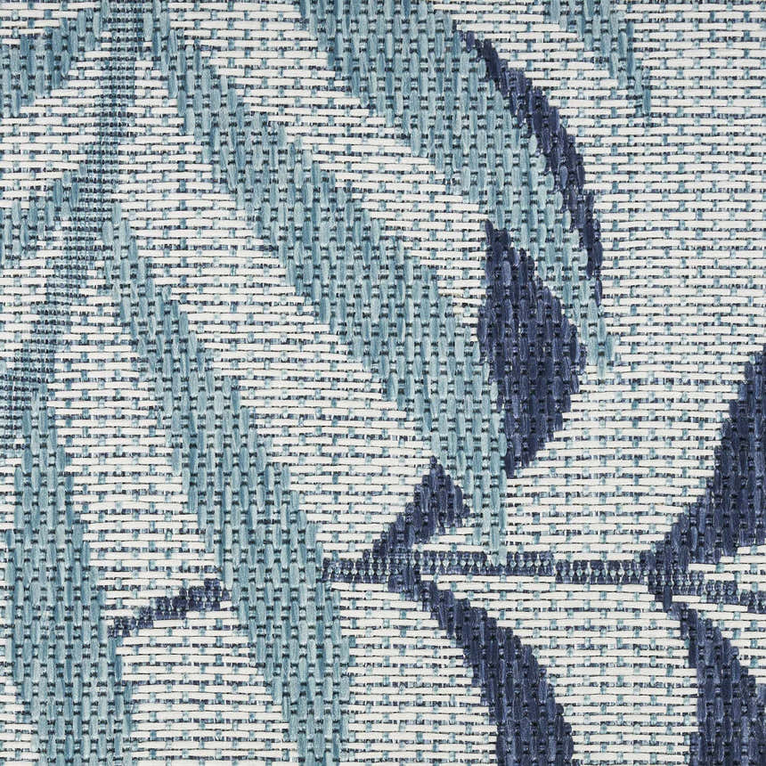 Close-up of the Nourison Garden Oasis Blue Tropical Area Rug showing a woven texture and blue leaf pattern.