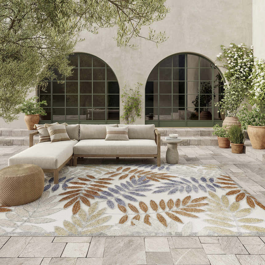 Outdoor patio with beige sofa and Nourison Aloha Blue Mocha rug with leaf pattern.