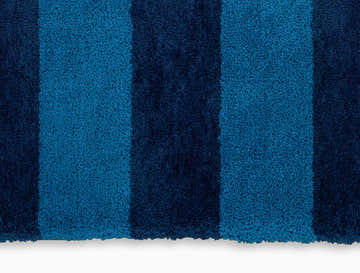 Close-up of the Calvin Klein Chicago Shag Rug. Blue striped shag rug with a soft, textured pile.