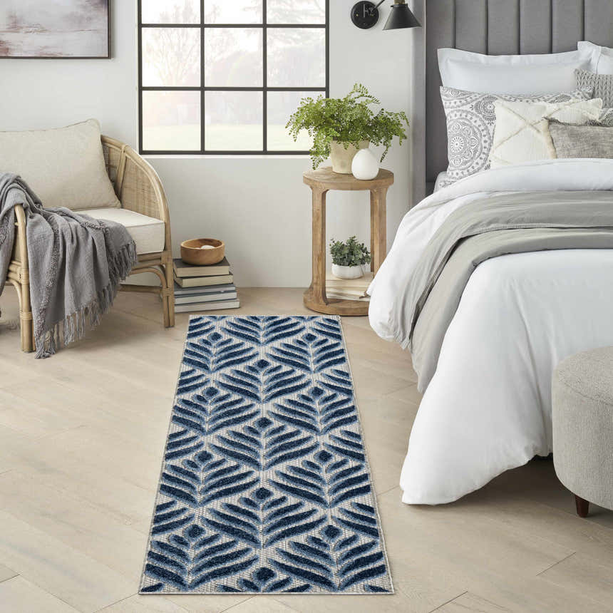 Bedroom scene with a Nourison Aloha Blue Outdoor Area Rug runner, light wood floors, and neutral decor.