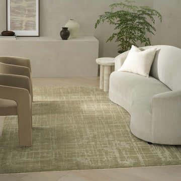 Modern living room with curved sofa and Calvin Klein CK090 Latitude Green rug. Neutral tones create a calming space.