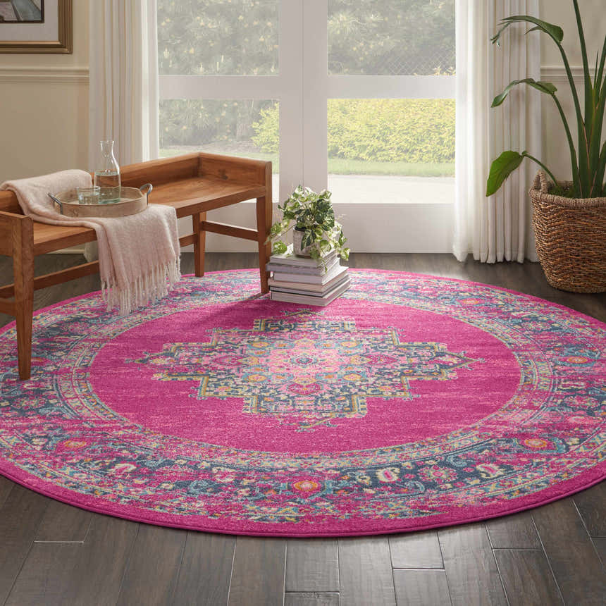 Sunlit room with Nourison Passion Fuchsia round rug, wood bench, and plant. Bohemian style.