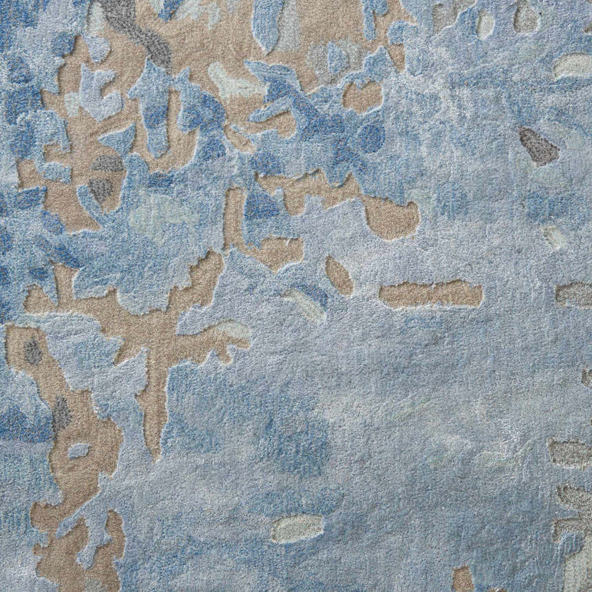 Close-up of the Nourison Prismatic Denim rug. Features an abstract pattern in denim blue, beige, and gray tones. Handmade wool texture.