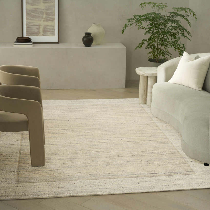 Living room scene with a Calvin Klein CK082 Ridge Ivory rug, curved sofa, and modern decor in neutral tones.