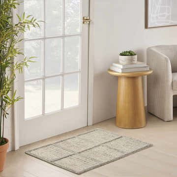 Entryway scene with a DKNY Pure Framework Silver rug, bamboo plant, and wood side table.
