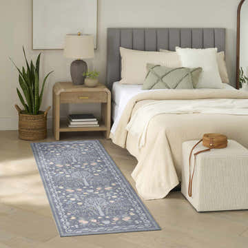 Bedroom scene with Nourison Botanical s Blue Multicolor rug, wood floors, neutral bedding, and modern decor.