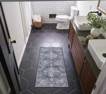 Bathroom scene with Nourison New Concept Ivory Navy Vintage Rug on black hexagon tile floor. Double sink vanity.