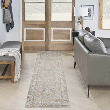 Entryway with a beige vintage Nourison Astra runner rug, gray bench, and leather sofa.