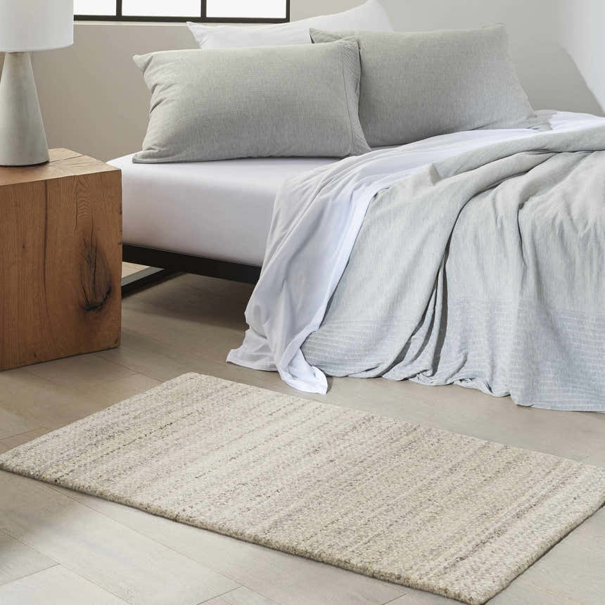 Calvin Klein CK040 Abrash Grey rug in a modern bedroom with gray bedding, wood nightstand, and light wood floors.