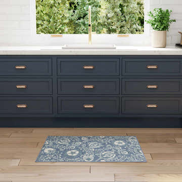 Farmhouse kitchen scene with Nourison Aloha Blue Area Rug, navy cabinets, wood floors, and gold faucet.