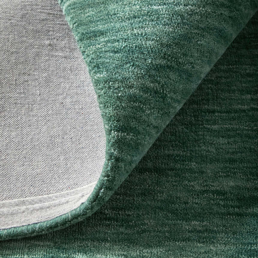 Close-up of the Feizy Luna Modern Solid rug in green and white, showing the wool texture and cotton backing. Fold