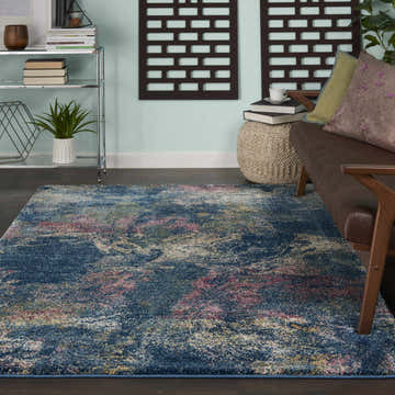 Living room scene with Nourison Fusion Blue Multicolor Artistic rug, brown leather sofa, and modern shelving.