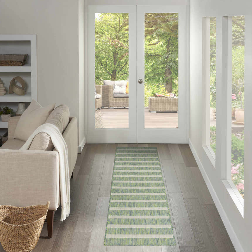 Hallway with a Nourison Positano Blue Green Ivory runner rug leading to a patio. Neutral furniture and light wood floors.