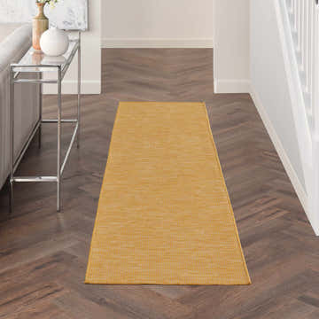 Hallway scene with a Nourison Positano Yellow runner rug on dark herringbone wood floors. Modern console table.