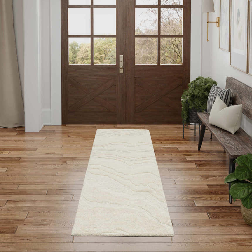 Entryway with wood floors, bench, and Nourison Graceful Ivory rug runner leading to brown double doors.
