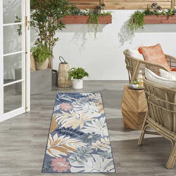 Outdoor patio with rattan chairs and Nourison Suncoast Denim Multicolor Tropical Area Rug runner.