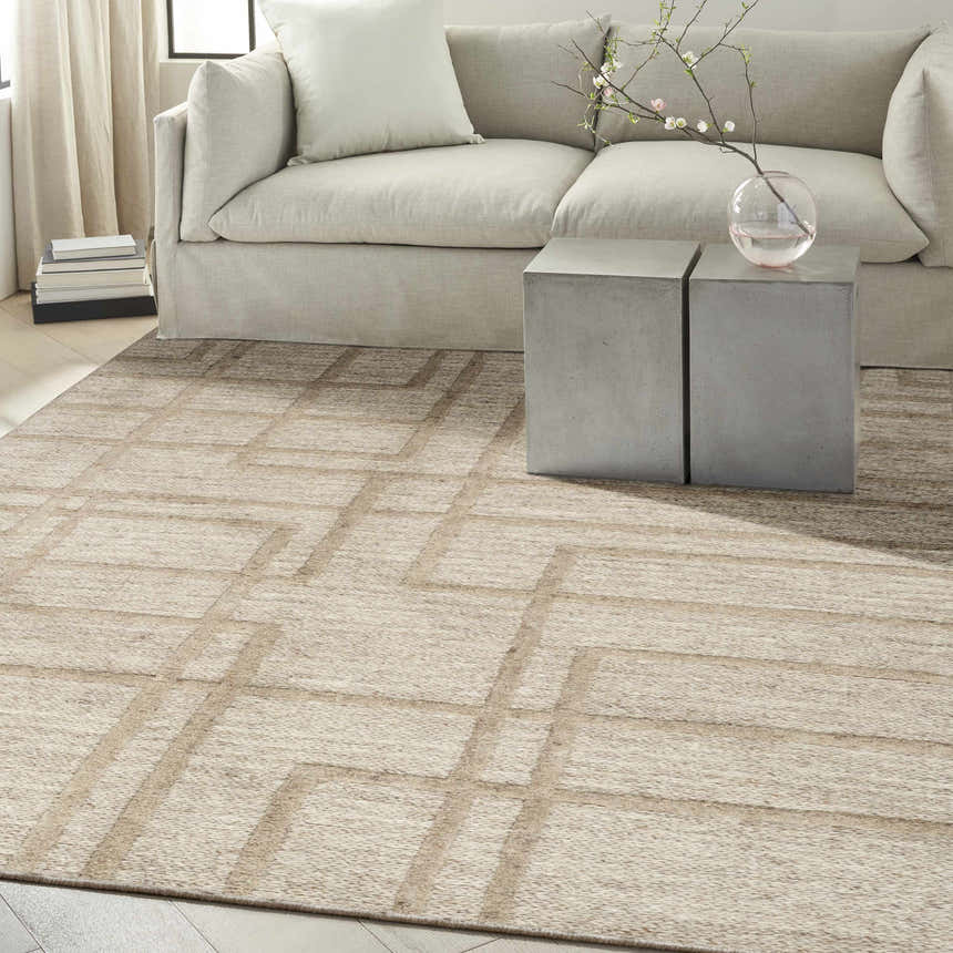 Modern living room with a camel-colored Calvin Klein CK045 Impressions wool rug, sofa, and concrete side tables.