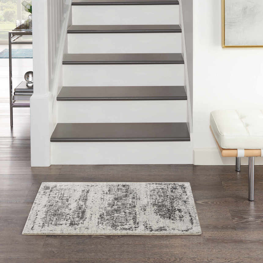 Entryway scene with Nourison Harmony Ivory Charcoal rug, white stairs, wood floors, and white bench.