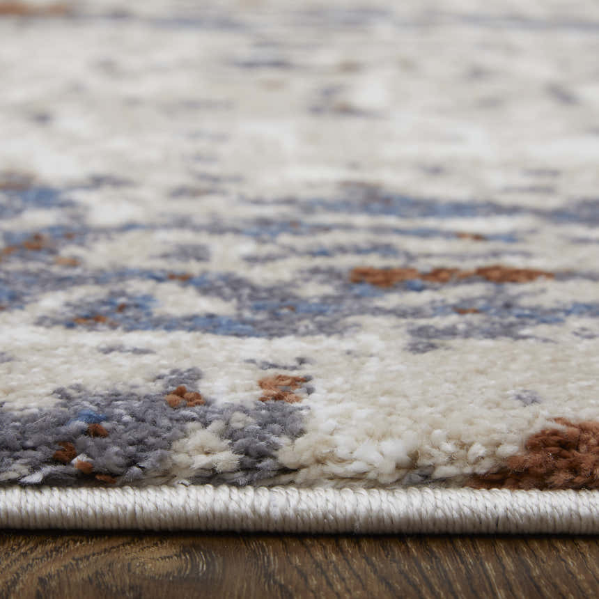 Close-up of Feizy Gilmore rug showing abstract ivory, blue, and gray pattern and textured polypropylene pile. Pile